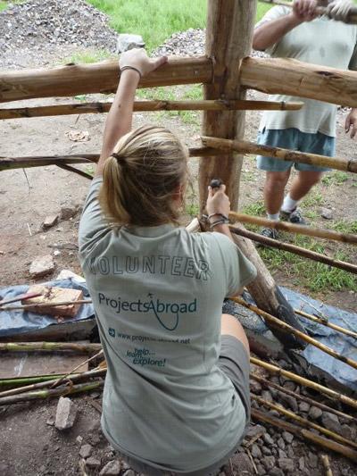 Volunteer on a Building project during a gap year abroad A volunteer working hard on building a wooden frame on a Building project